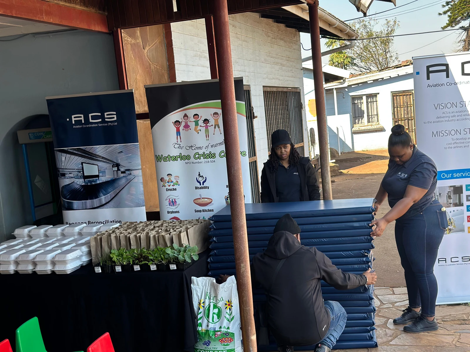 ACS team members preparing food, seedlings and mattresses for a community support initiative